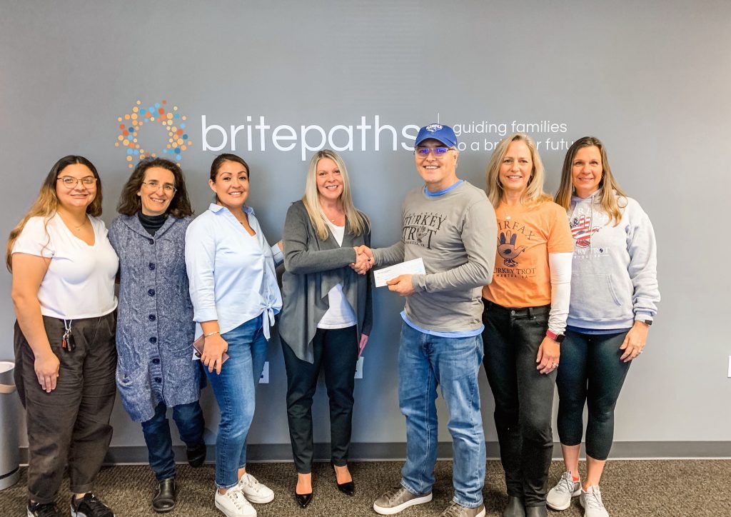 Fairfax Turkey Trot organizers present Britepaths staff with a check from the November 24, 2022 race